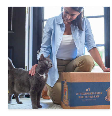 een vrouw met haar harige zwarte kat en een verpakking Hill's kattenvoer