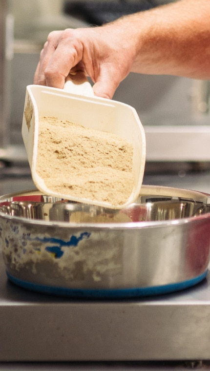 A Hill’s employee measuring ingredients on a scale